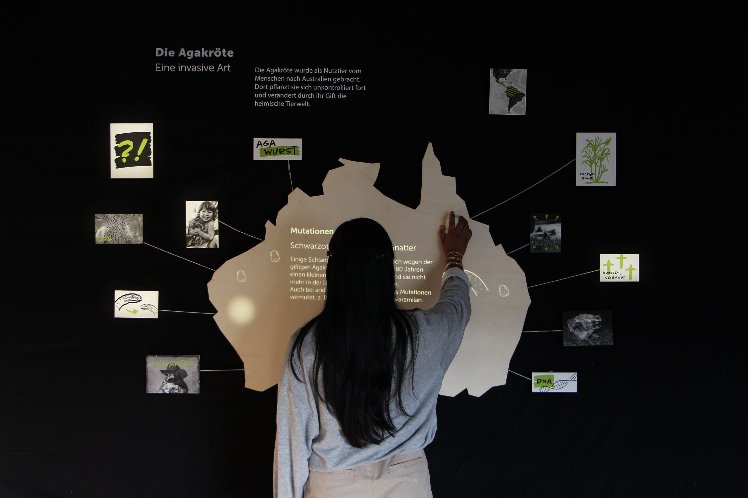 a woman moving a tangible object on a exhibit that looks like a dedetive wall.